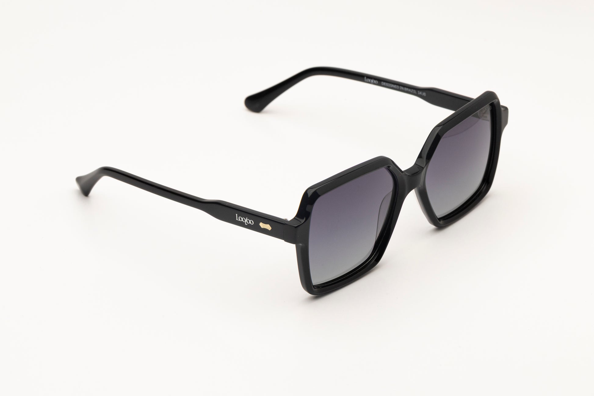Sunglasses with black acetate frame with gradient lenses, on a white background.