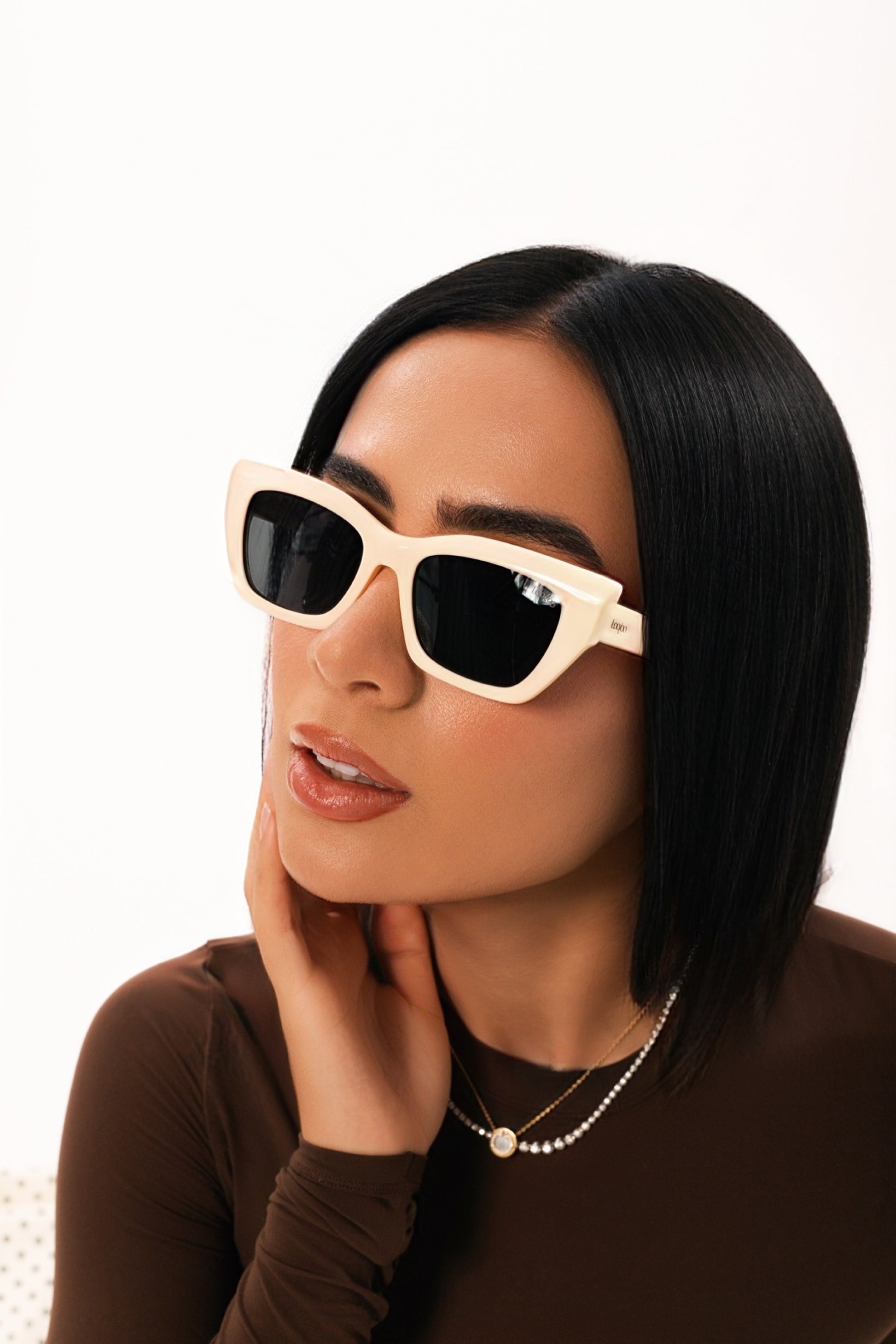 Woman wearing brown outfit, wearing a pair of beige acetate frame sunglasses, on a white background.