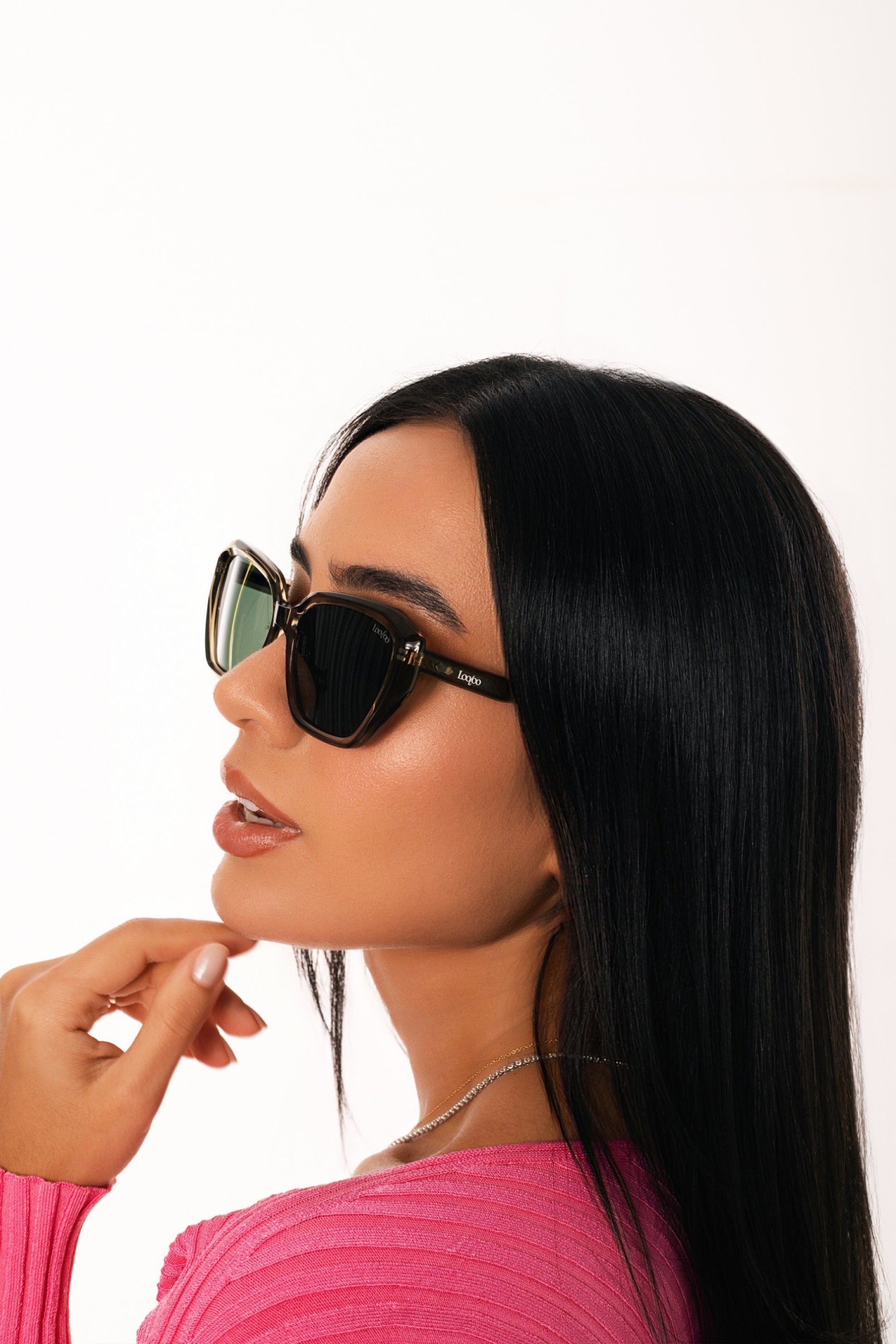 Woman wearing pink shirt wearing a pair of green acetate frame and green lenses sunglasses, on a white background.