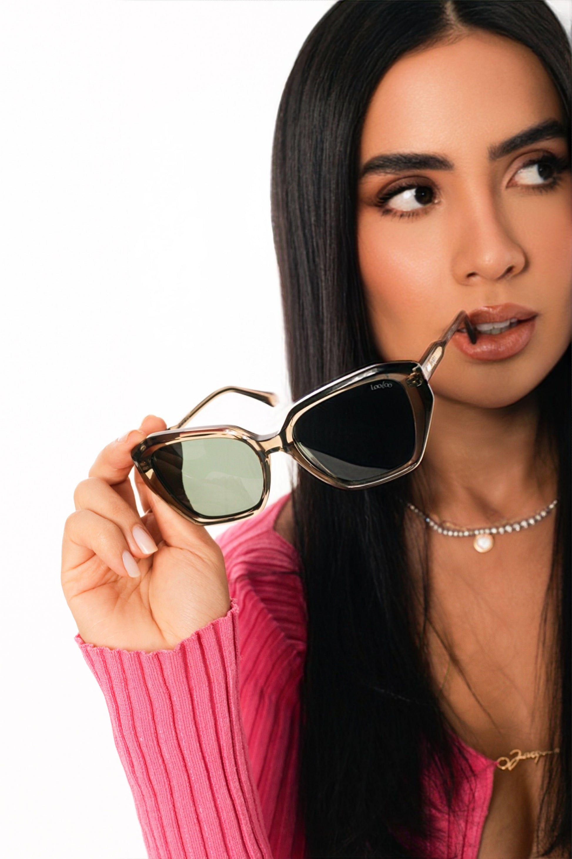 Woman wearing pink sleeve holding a pair of green acetate frame and green lenses sunglasses, on a white background