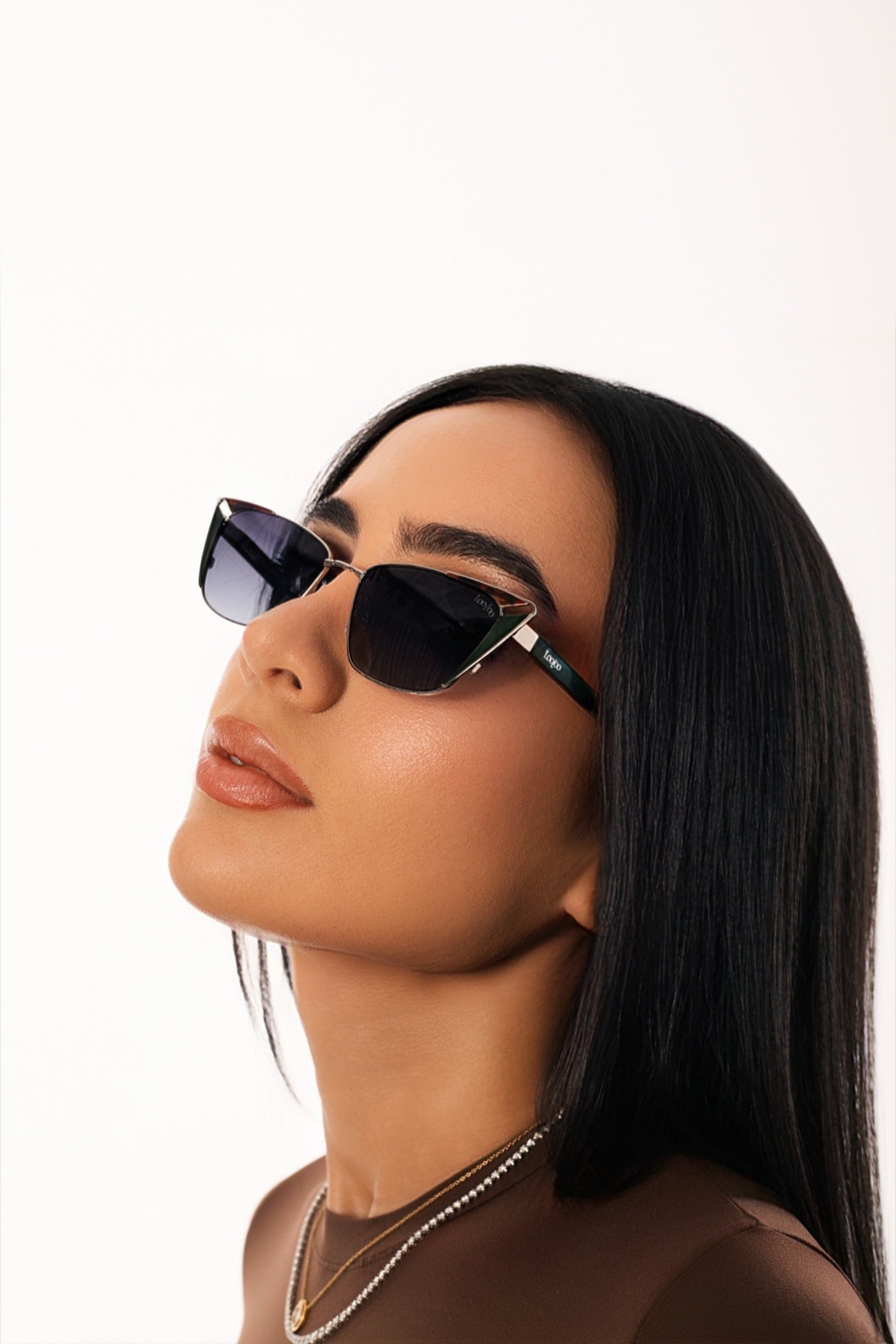 Woman wearing brown outfit, wearing a pair of black acetate and metal frame sunglasses, on a white background.